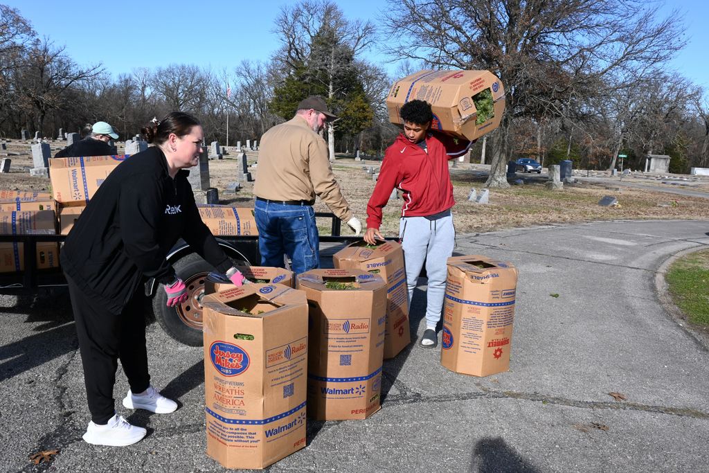 Athletes unload the boxes of wreaths from the trailer.
