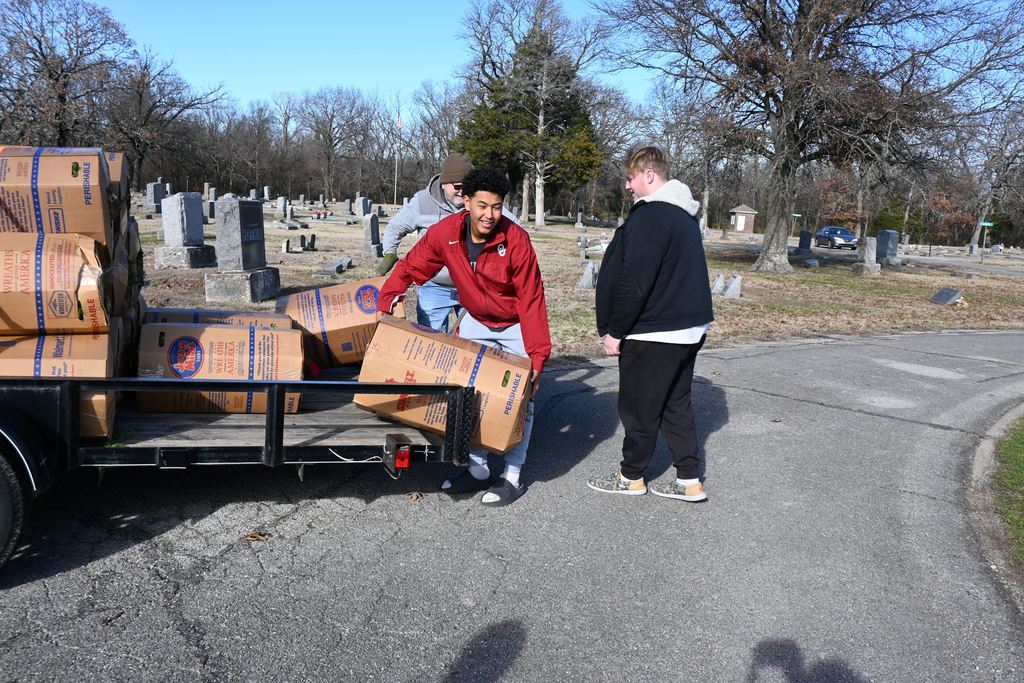 Athletes unload the boxes of wreaths from the trailer.