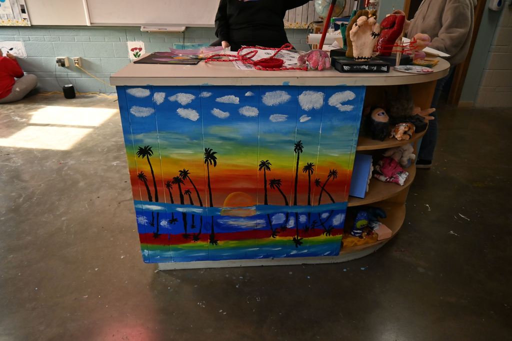 A mural of palm trees and a sunset  reflected in water.