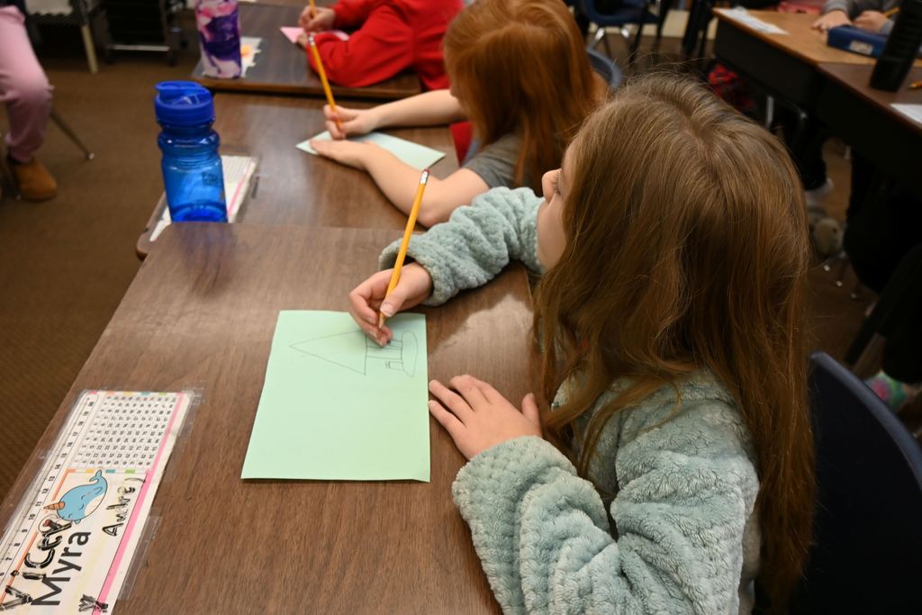 Students draw out Christmas cards with a penicl before decorating them.