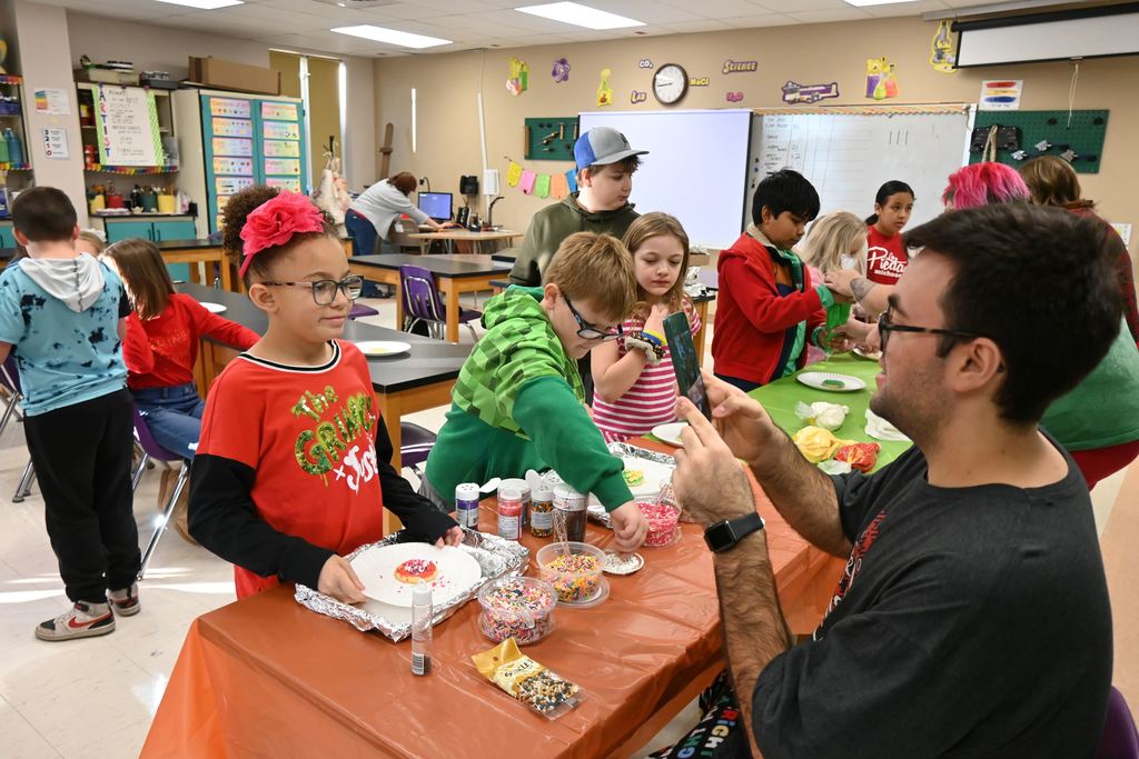 Mr. Holmes takes a picture of a student with her finished cookie.