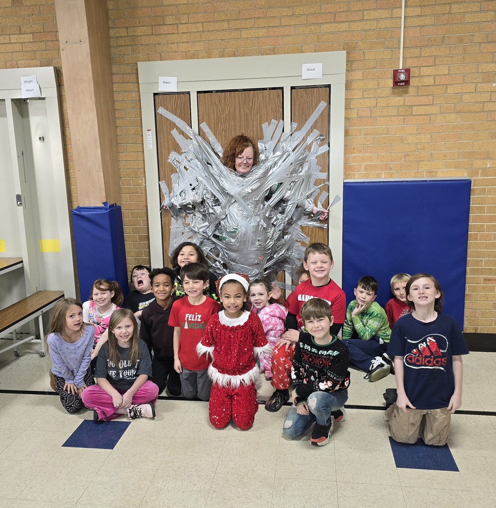 students kneeling in front of their teacher who is taped to a wall