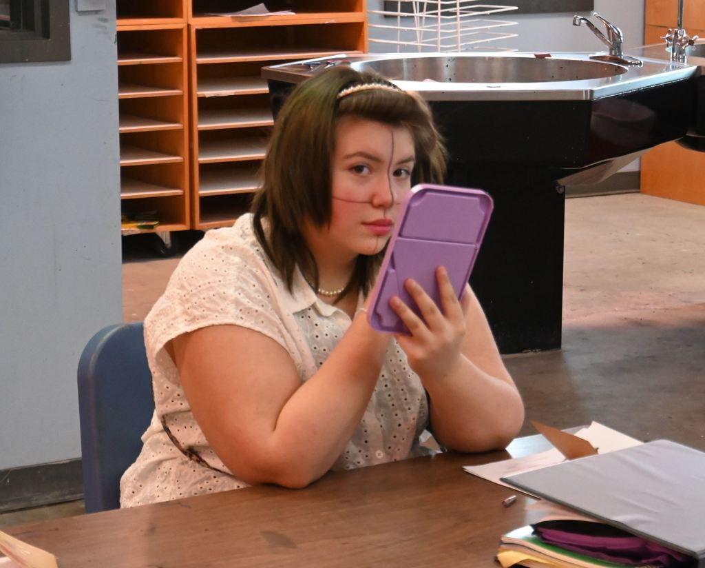 A student uses eyeliner on herself to define sections nad aide in understanding porportions.