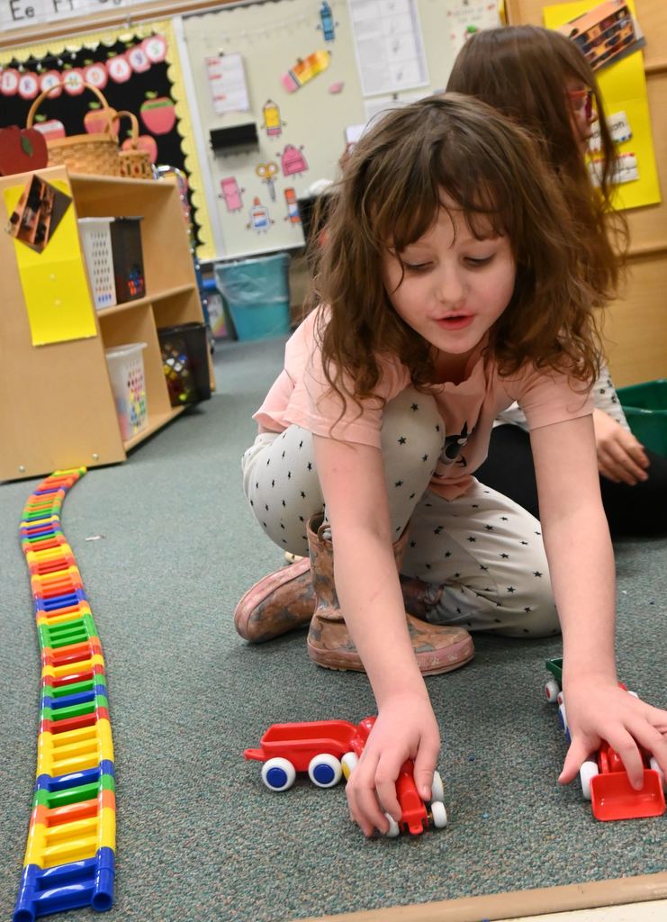 A student built train ttracks and puts together her train.