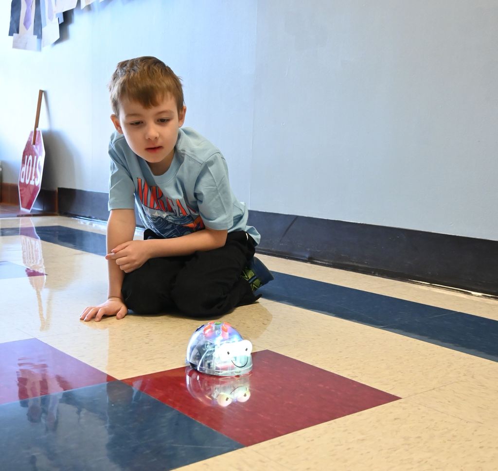A boy plays with a coding robot.