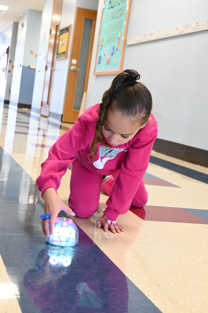 A girl plays with a coding robot.