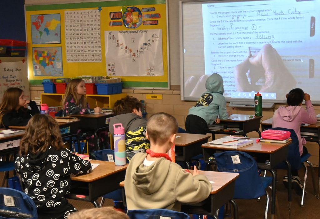 Mrs. Keal waits for a student to provide an answer for her to write in during  a group language arts lesson.