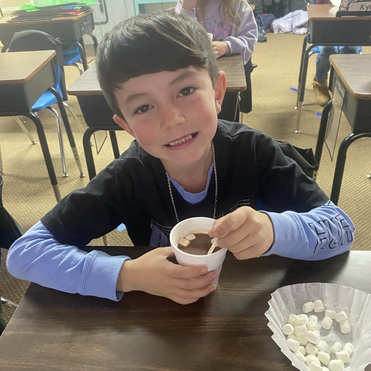 student drinking hot chocolate at their desk