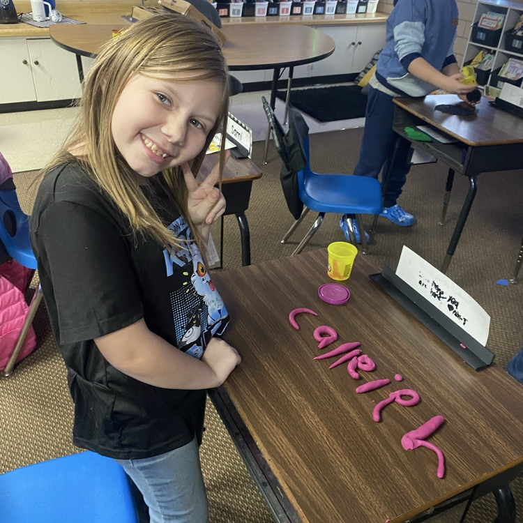 student using Play-Doh to fill out their name