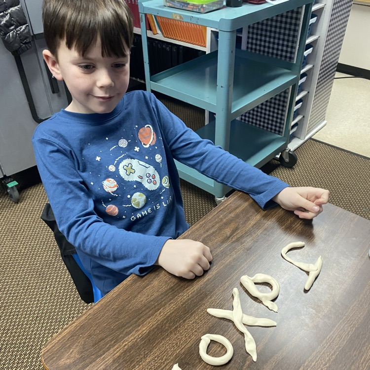 student using Play-Doh to fill out their name