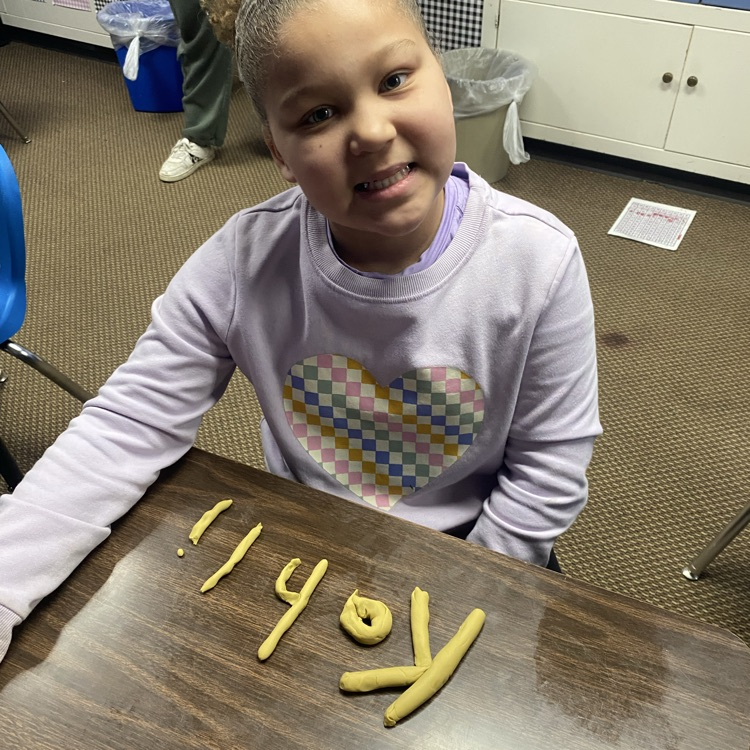 student using Play-Doh to fill out their name