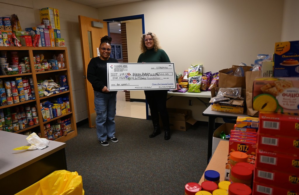 Kristina Mayhue receives holds up an oversized check presented by Becky Dantic.