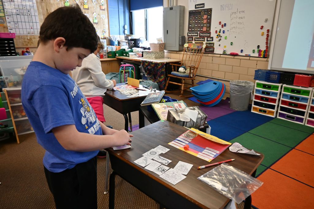 Students glue pictures and descriptions into flip books.