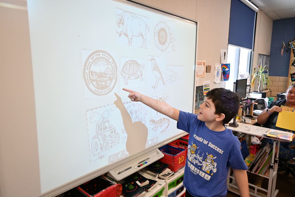 a student points out the answer on a screen to a question about Kansas .