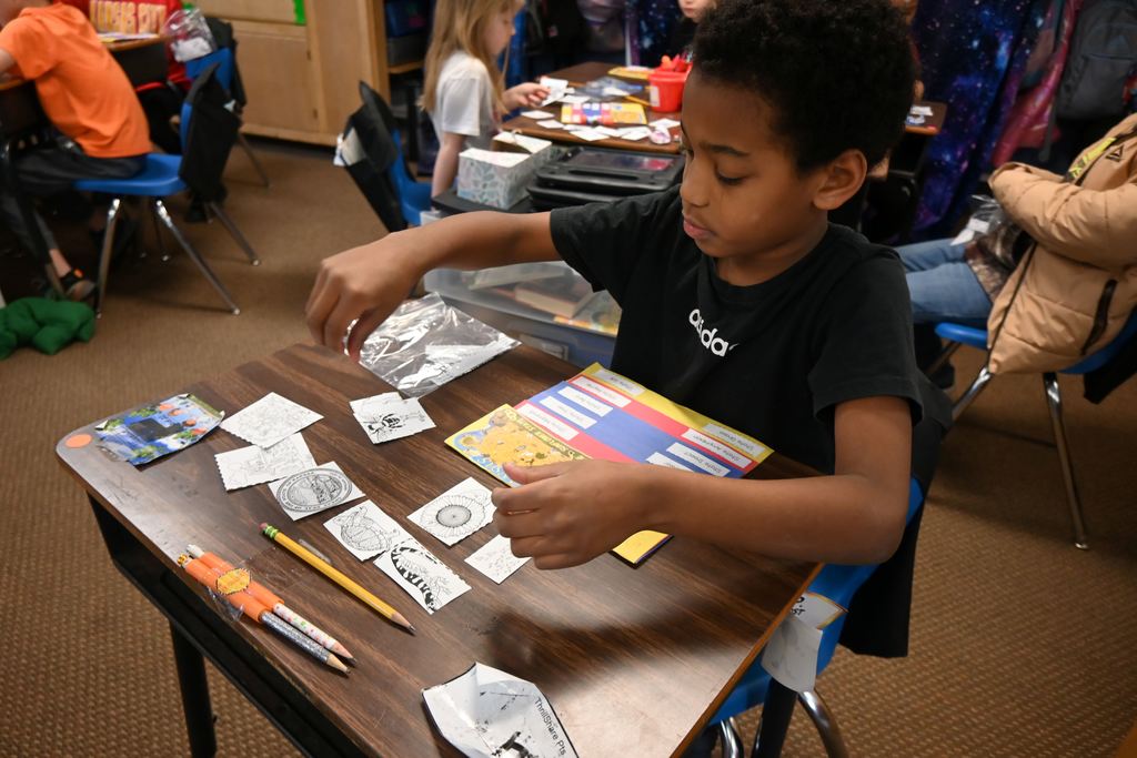A boy lays put all the various symbols representating the state of Kansas.