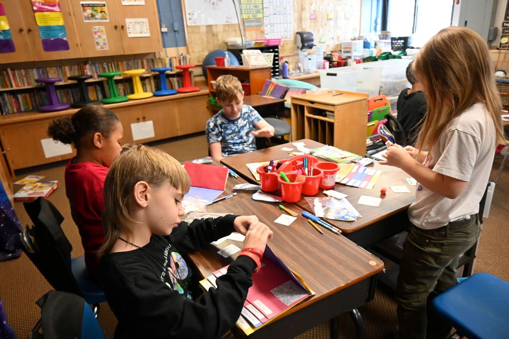 Students glue pictures and descriptions into flip books.