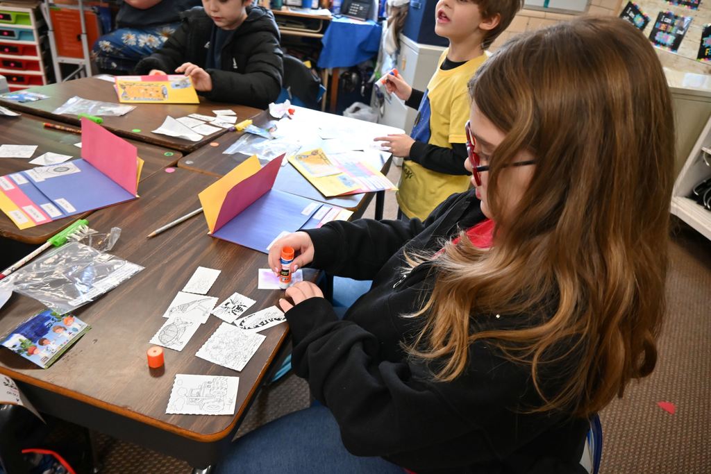 Students glue pictures and descriptions into flip books.
