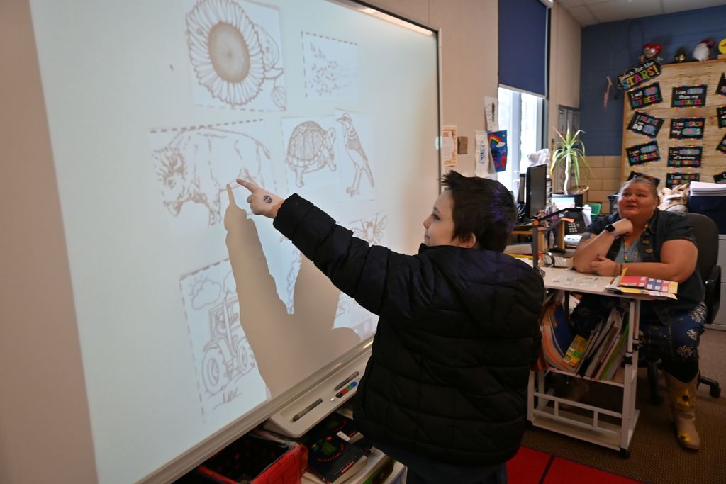a student points out the answer on a screen to a question about Kansas .