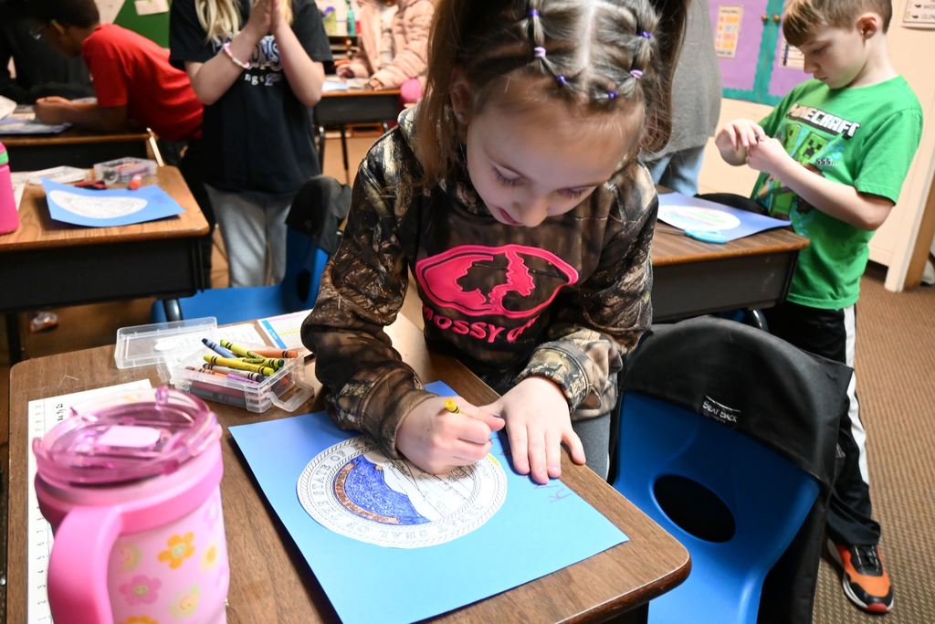 A student colors the Kansas Seal on a state flag they are making.