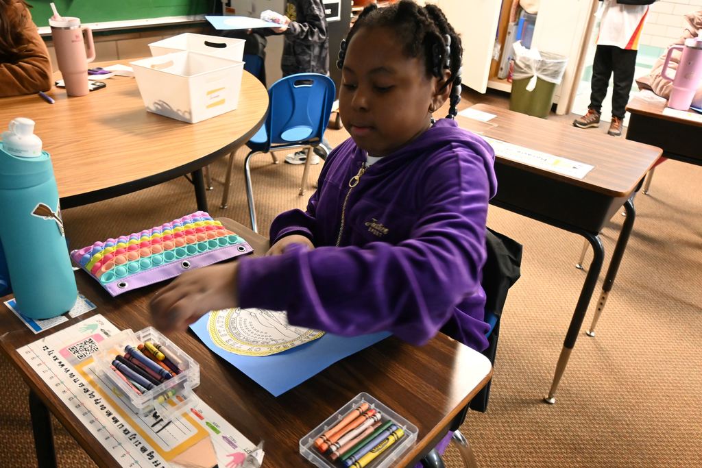 A student colors the Kansas Seal on a state flag they are making.