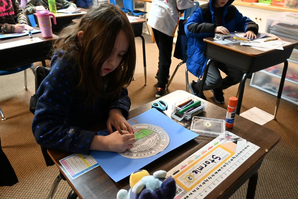 A student colors the Kansas Seal on a state flag they are making.