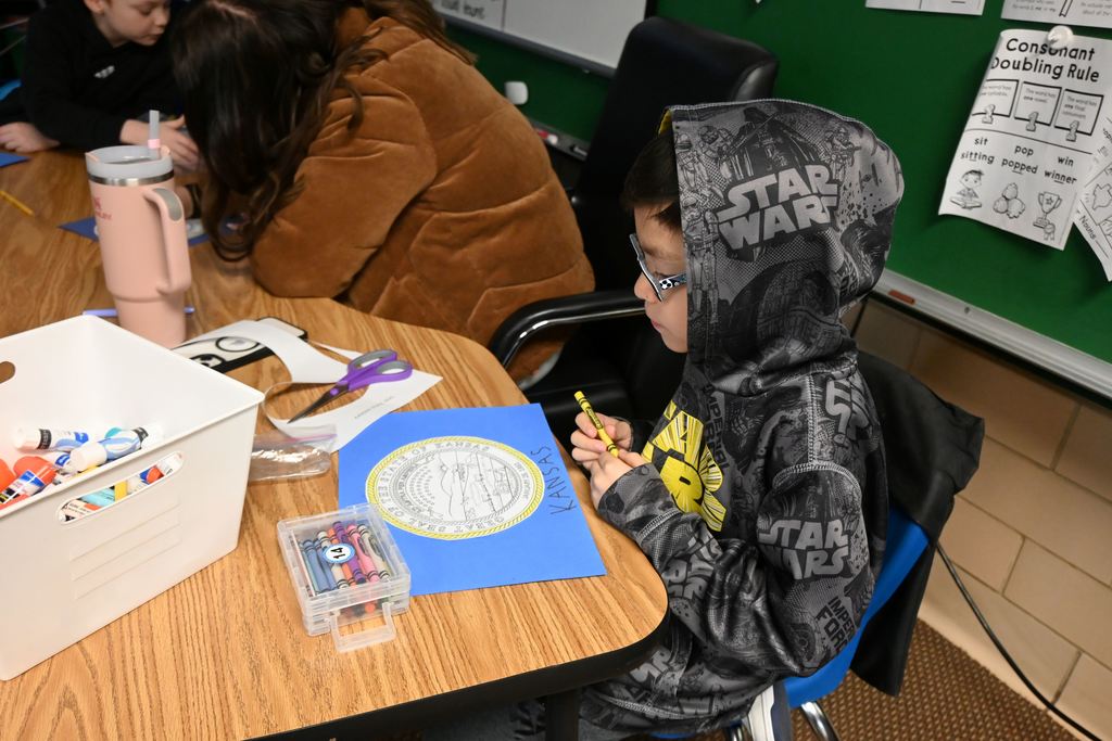 A student colors the Kansas Seal on a state flag they are making.