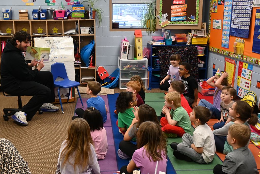 A senior reads to kindergarten students.