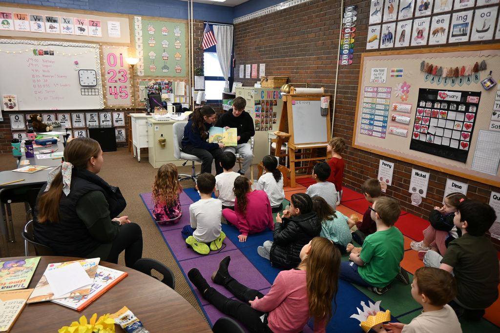 Mrs. Hutley's brother and another high school student read a story to her class.