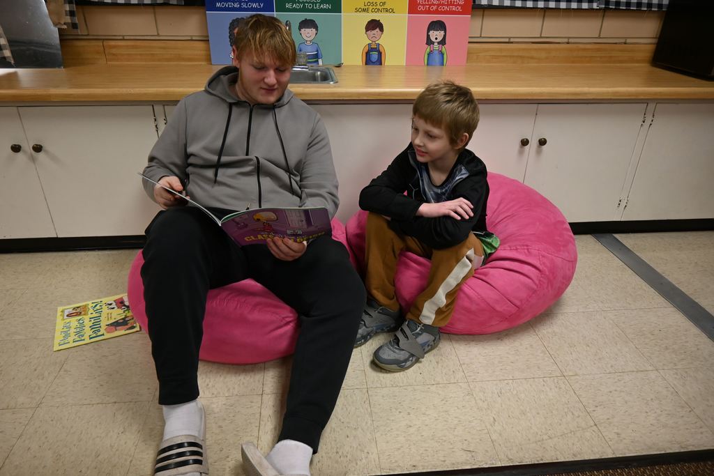 A high school athlete reads to a Garfield student.