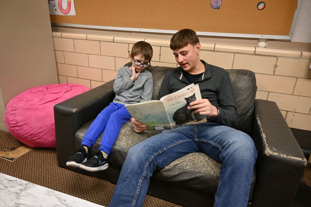 A high school student reads to an Garfield student one on one.