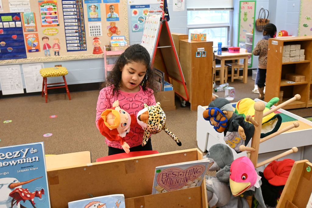 A little girl plays with a  king hand puppet and an leopard hand puppet.