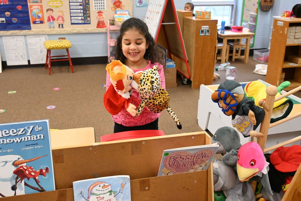 A little girl plays with a  king hand puppet and an leopard hand puppet.