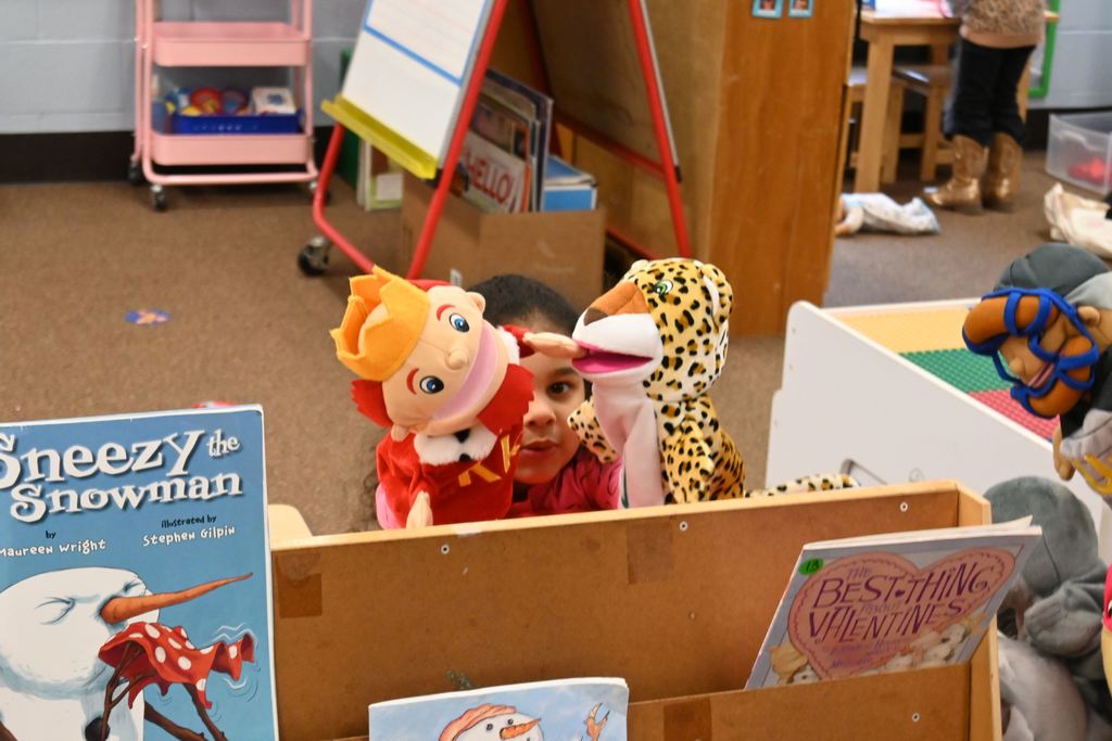 A little girl plays with a  king hand puppet and an leopard hand puppet.