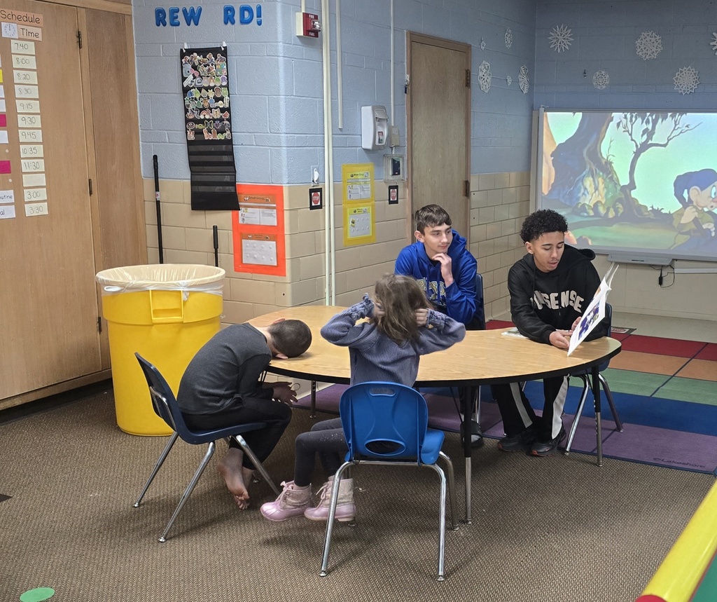 two teen boys reading to young kids