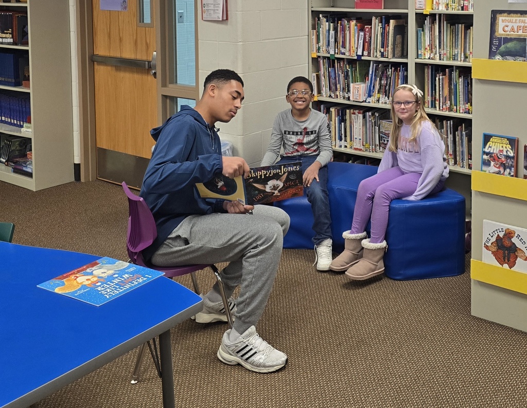 teen boy reading to a young boy and girl