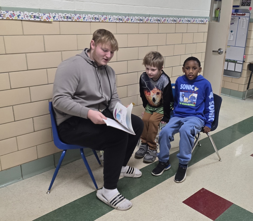 teen boy reading to two younger boys in the hall