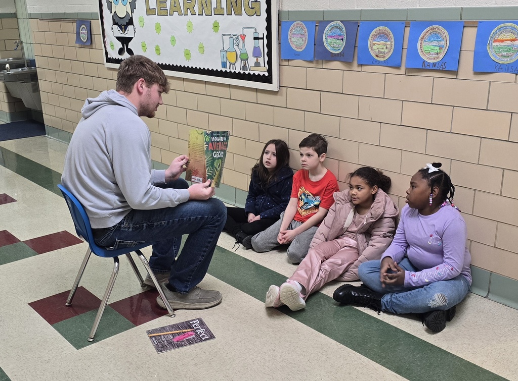 teen boy reading to a group of students in the hall