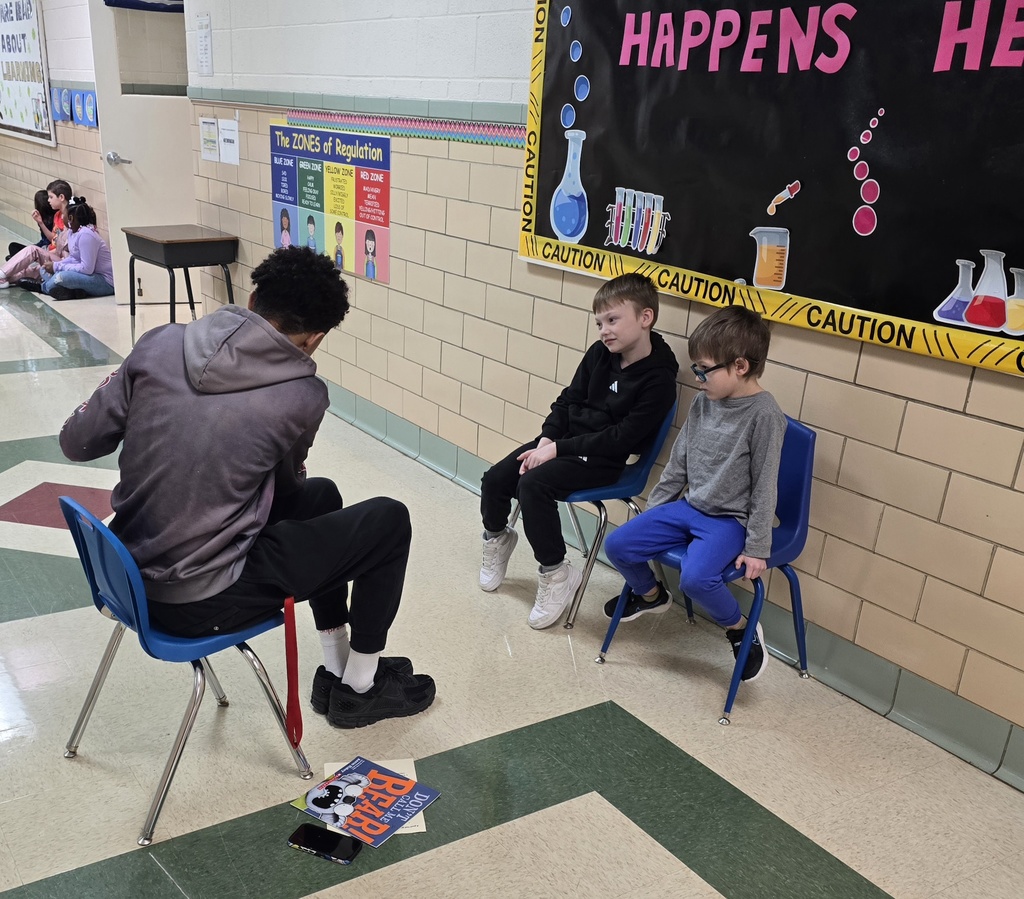 teen boy reading to two young boys