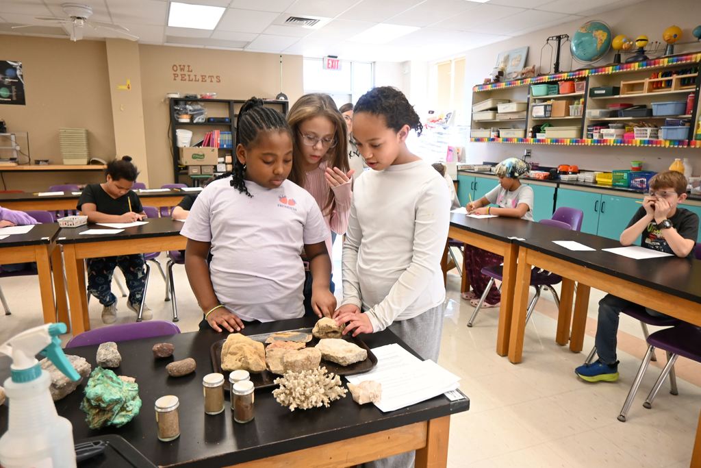 Three giels look at the rocks and fossils.