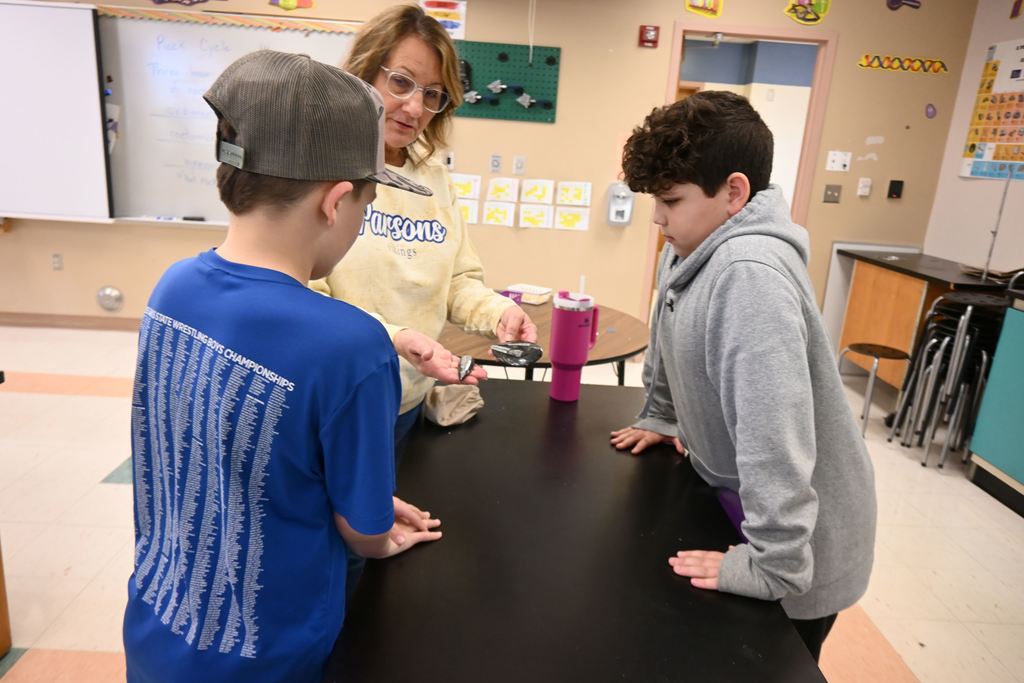 Mrs. Piva explains fossils iof creatures seen in two of the polished rocks she brought.