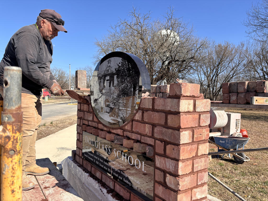 Fifth generation mason Doug Strong cleans mortar  from under the freshly laid granite oval featuring aan engraved photo of Douglass School, as the memorial for the school nears completion.