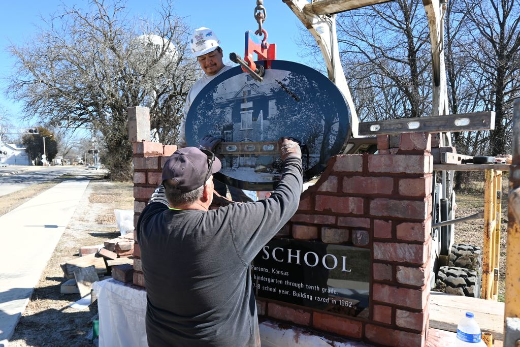 Doug Strong holds up a level determining last minute adjustments before setting the granite oval for the memorial in place.