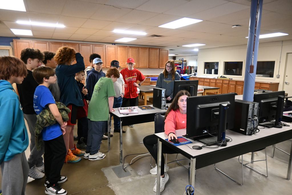 Students learn from a yearbook staff member about taking pictures and designing  the yearbook.