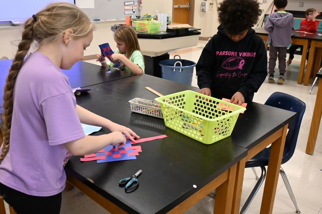 Two students work on weaving paper.
