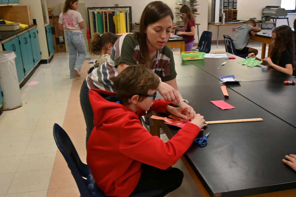 Mrs. Hunn guiides a student in finishing steps of his weaving.