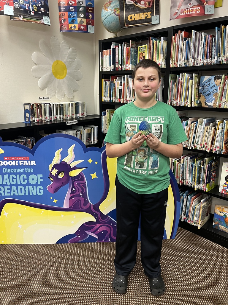 Fifth grade Book Fair Winner next pictured with other fifth graders  of dragon items  (3D dragon, dragon with egg, and dragon egg fidget)