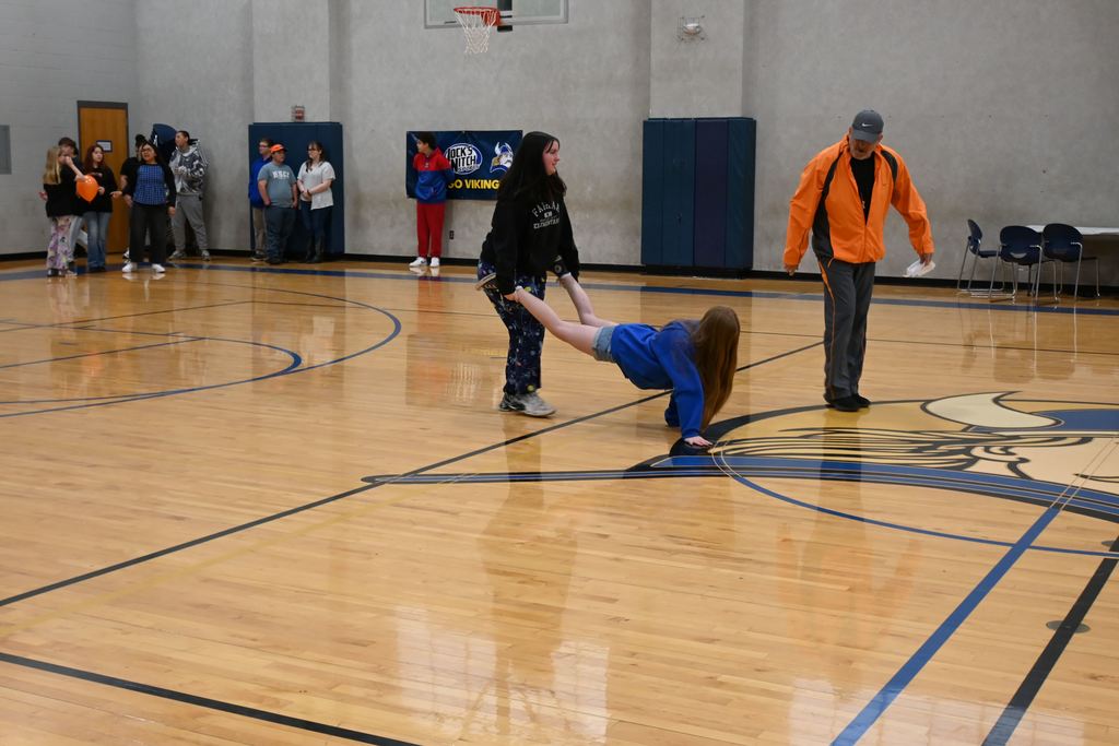 Two girls are engaged in the wheelbarrow race portion of a relay.