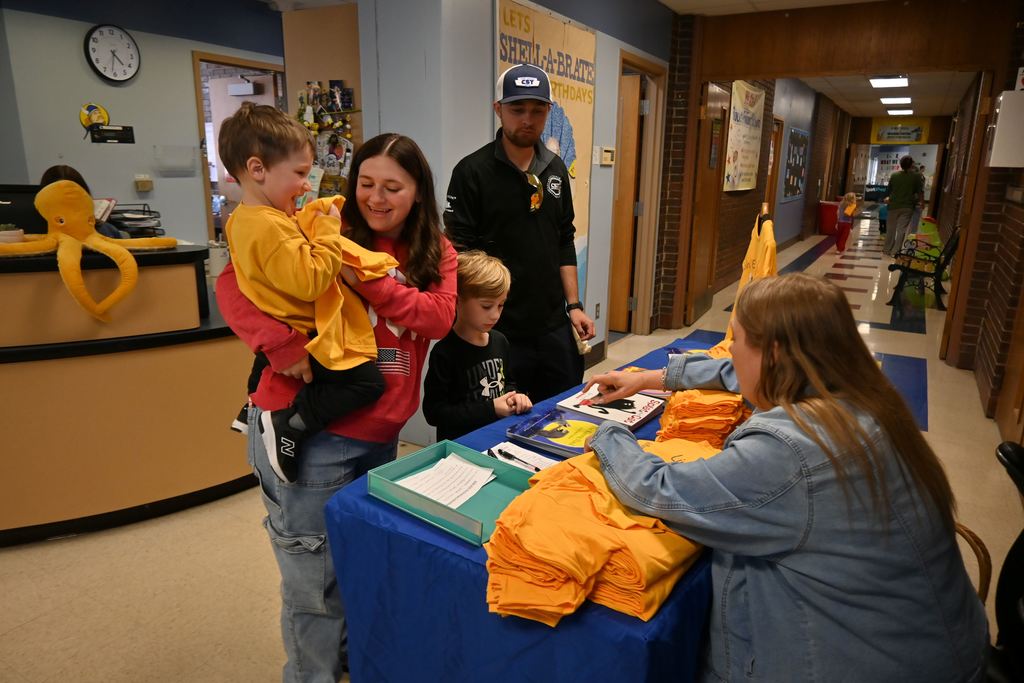 A mom hands her son a new T-shirt given out to the first 100 children who came.