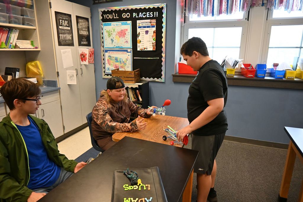 Three boys discuss their bottle balloon cars.
