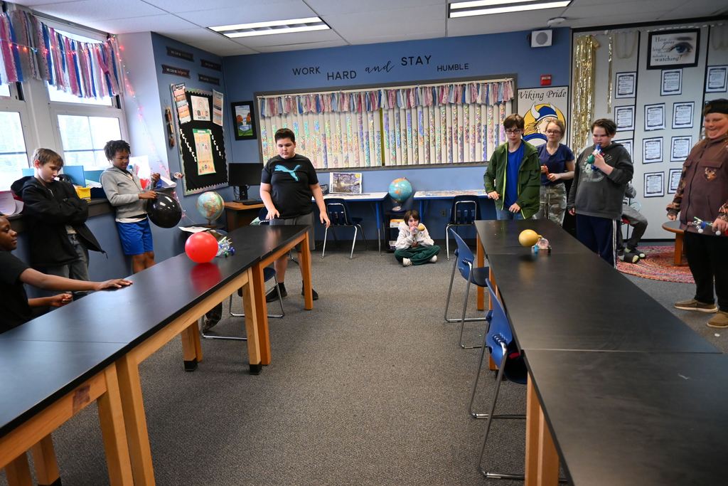 Two students race their cars as others watch.